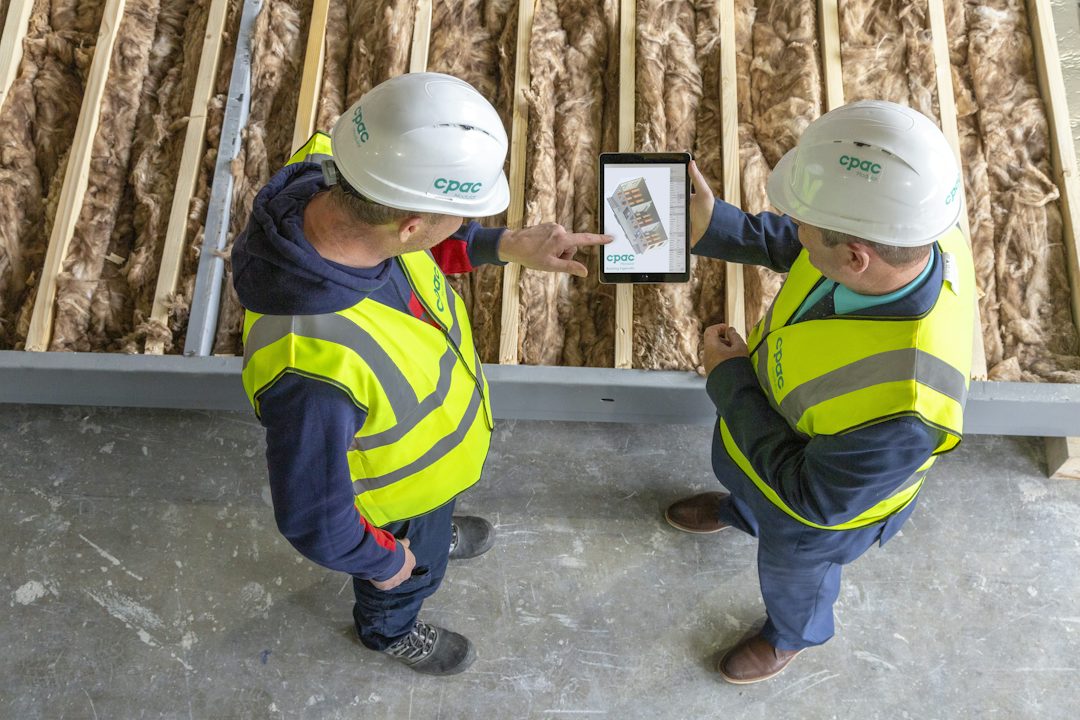 Two site staff in hi-vis reviewing a drawing on a tablet