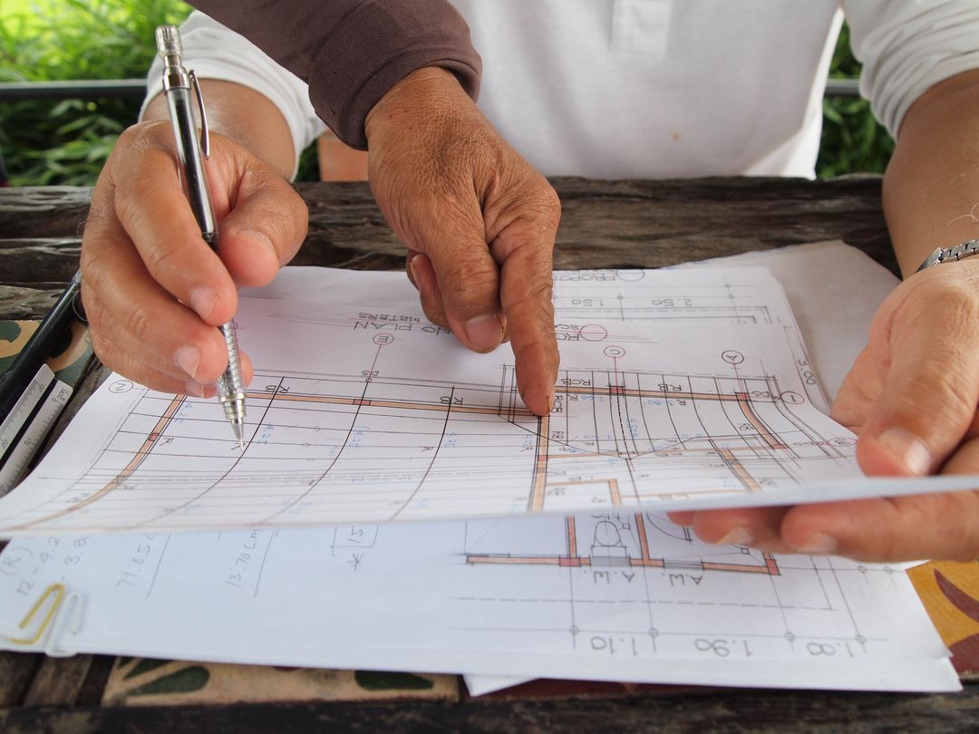 Hands marking up a floor plan with a pencil
