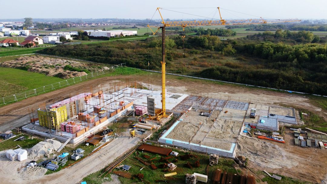Aerial view of a mid-rise site with a tower crane, foundations and staged materials